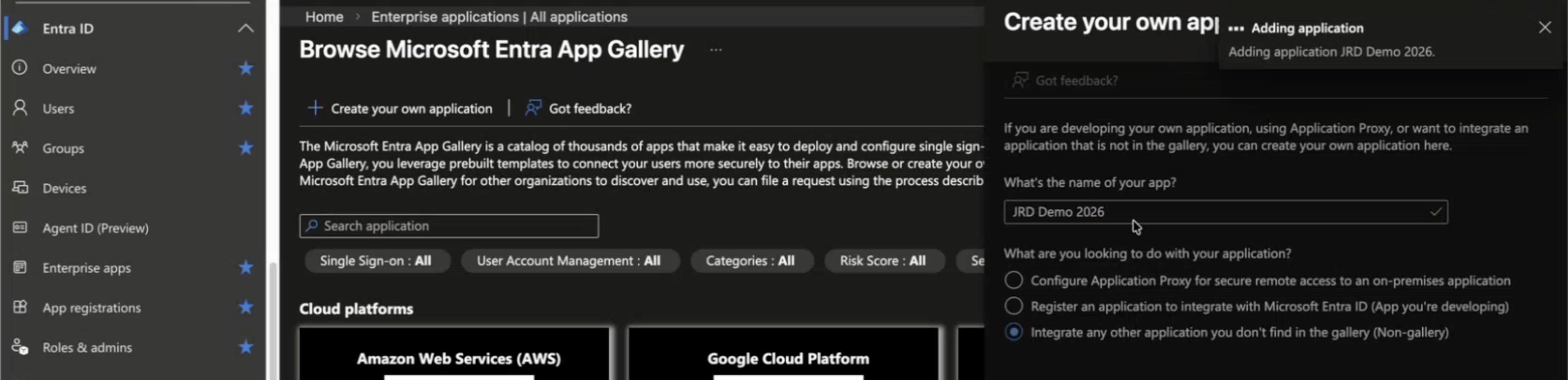 Microsoft Entra Admin Center interface showing navigation menu with options like Overview, Users, Groups, and Devices. Main section displays Browse Microsoft Entra App Gallery page with filters for Single Sign-On, User Account Management, Categories, and Risk Score. A pop-up window titled Create your own application shows a form for adding an app named JRD Demo 2026 with Non-gallery integration selected.
